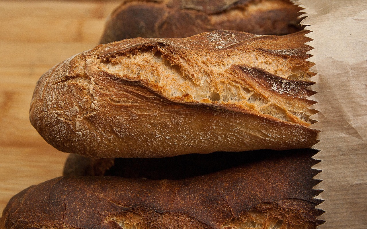 Crusty loaves in a paper bag on a wooden board